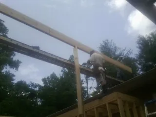Carpenter setting a ridge beam over a new addition frame — Ice Dam Removal by Roofing Brothers in Delmar