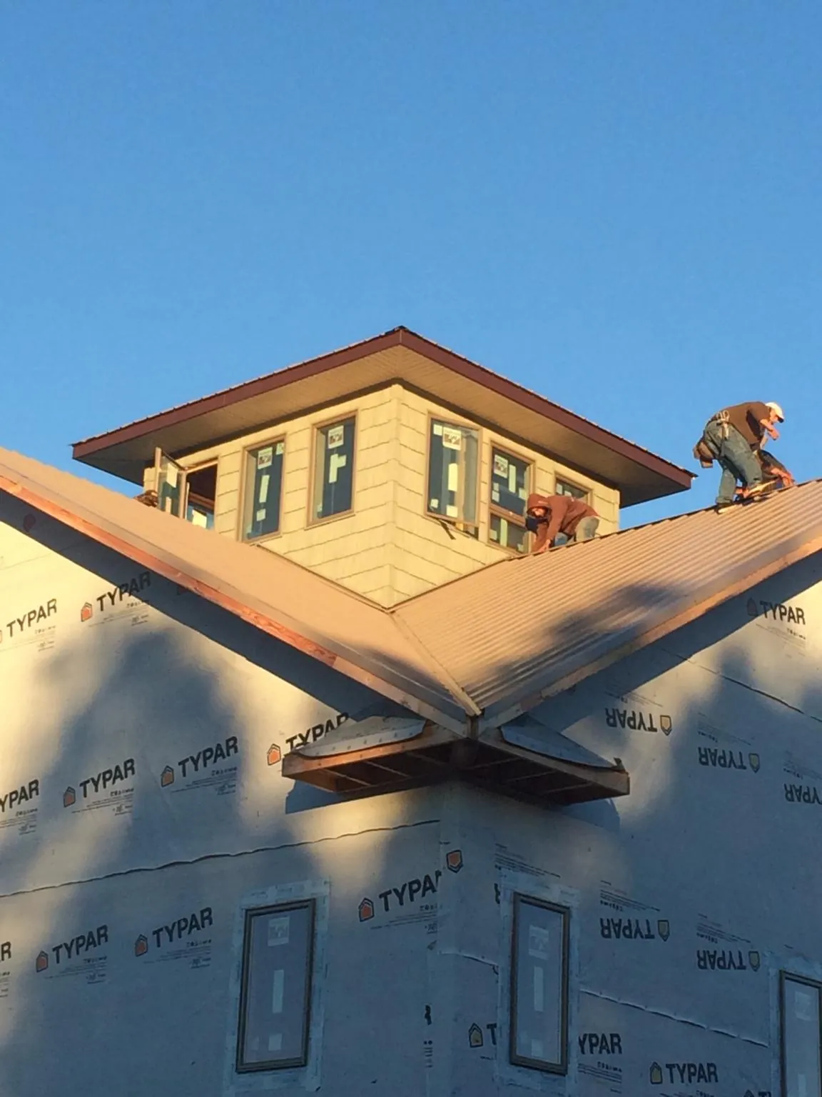 Roofers working around a rooftop cupola on a new metal roof at sunset — Roof Waterproofing in Delmar by Roofing Brothers
